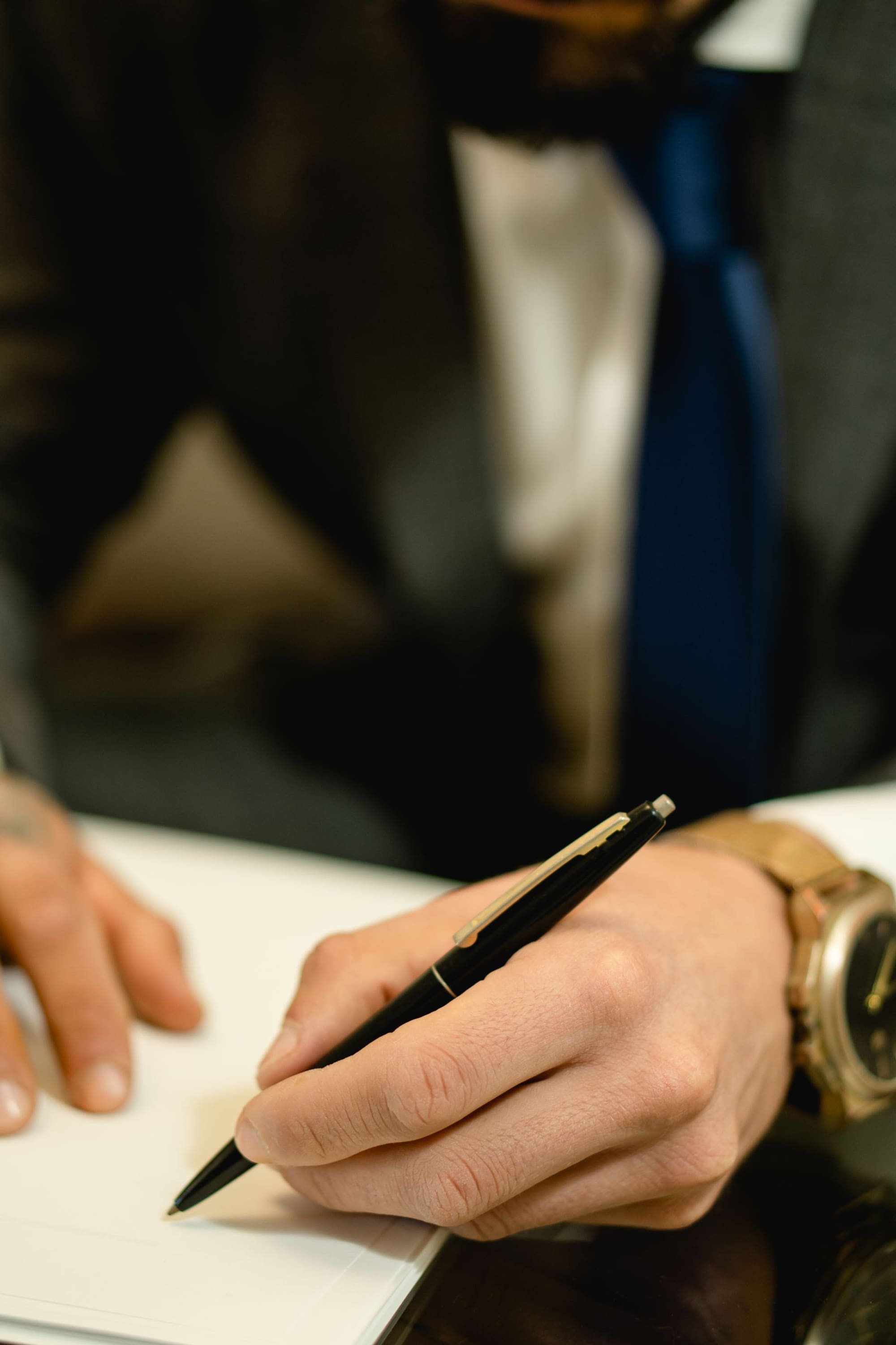 חתימה בעט על מסמך, ידיו של אדם בחליפה